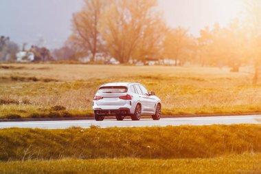 Lüks SUV bir kır yolunda ilerliyor.