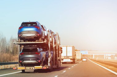 İki katlı karavanda yepyeni SUV taşıyan bir kamyon.