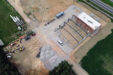 Kazı makinesi ve malzemelerle kırsal inşaat alanının hava görüntüsü.