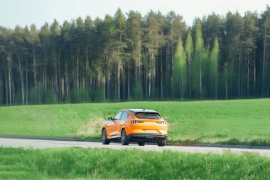 Elektrikli Turuncu SUV Huzurlu Kırsal Bölgede Seyahat Ediyor