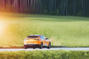 Elektrikli Turuncu SUV Huzurlu Kırsal Bölgede Seyahat Ediyor