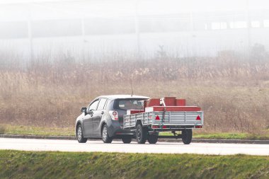 Karavanlı araba güneşli kırsal yolda.