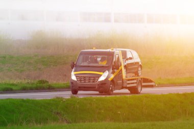 Çekici, işlek otoyolda bozuk araba taşıyor.