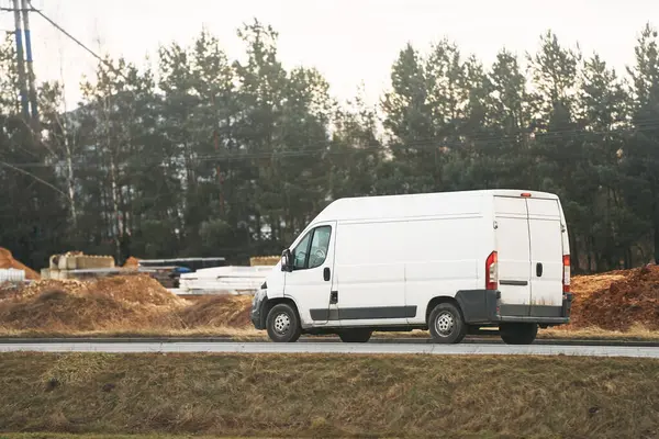 stock image Modern delivery van speeding along a sunlit highway with autumn foliage in the background