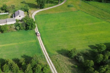 Yeşil tarım arazisindeki kırsal yolda traktörün hava görüntüsü