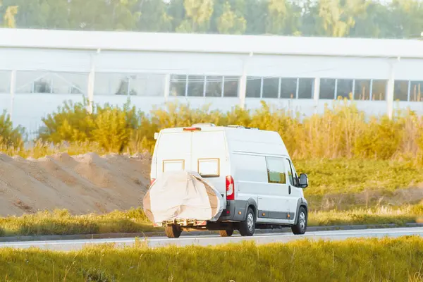 Karavan, yazın verimli kırsal bölgelerden geçen güneşli bir otoyolda bisiklet çekiyor.