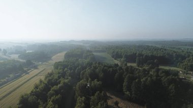Sabahın erken saatlerinde tarlaları ve ormanları olan manzaralı bir yer.