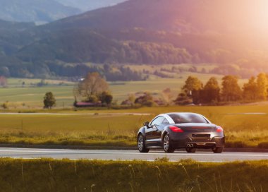 Dağların yakınındaki kırsal yolda giden araba.