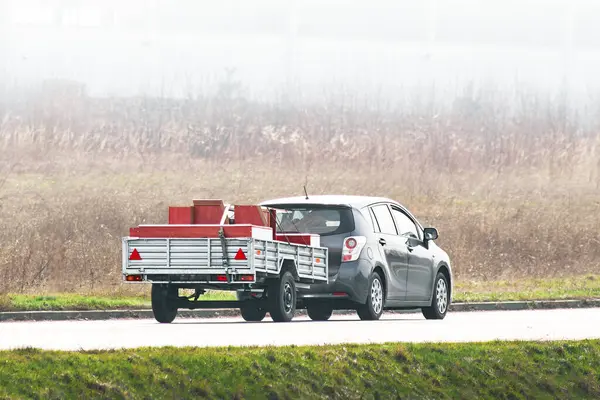 stock image Car pulling trailer through sunny landscape