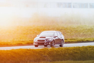 Mavi arazi arabası çimlerle ve binalarla çevrili cadde boyunca seyahat ediyor.