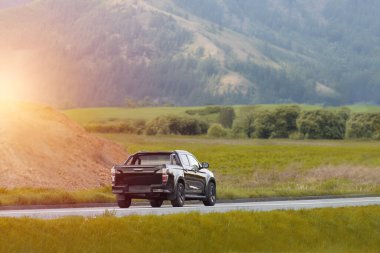 Gün batımında kırsal bir yolda siyah bir kamyonet.