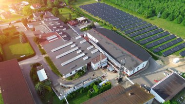 Kendini adamış bir güneş enerjisi santrali ile donatılmış endüstriyel üretim tesisinin havadan görüntüsü.