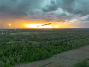 Uğursuz günbatımı gökyüzünün altında tarım arazileri ve ormanlar