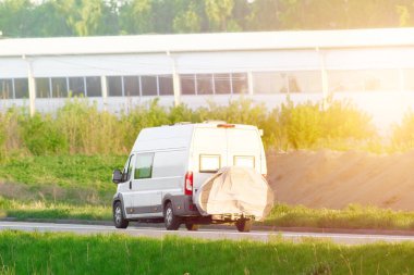 Yazın güneşli kır yolunda bisikletli beyaz bir karavan sürüyormuş.