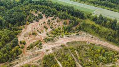 Toprak bisiklet yolu sık bir orman arazisinde dönüyor.