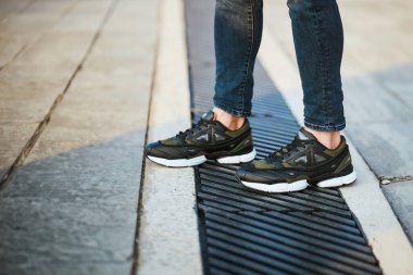 Koyu yeşil haki rengi spor ayakkabılar ve Taş Merdivenlerin Üzerinde Kot pantolonlar Yakından