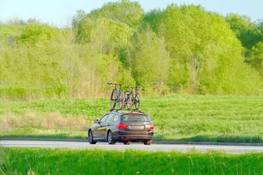 Dağ bisikletli aile arabası güneşli bir yolda gidiyor.