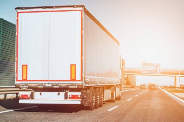 Kargo kamyonu güneşli yolda gidiyor.