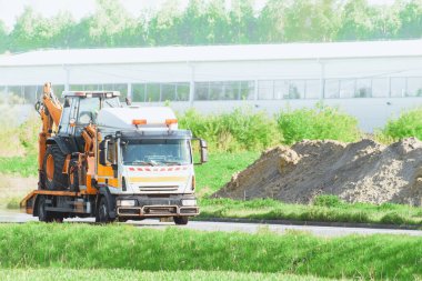 Güneşli bir yaz gününde, otoyolda mini kazıcılı bir çekici.