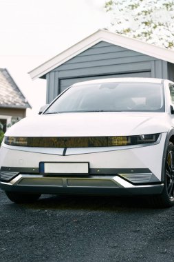 Banliyö evinin önüne park edilmiş modern beyaz elektrikli cip.