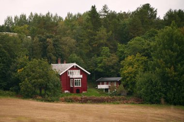 Turuncu çatılı ve bacalı kırmızı evin yakınına.