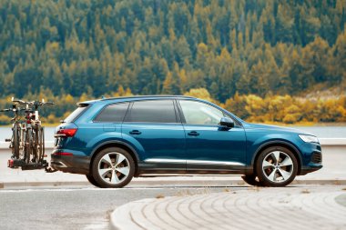 Göl ve ormanın yanındaki yolda giden bir araba.