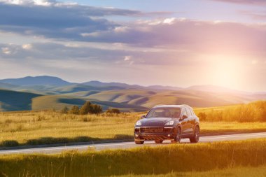 Siyah Alman SUV gün batımında bir kır yolunda gidiyor.