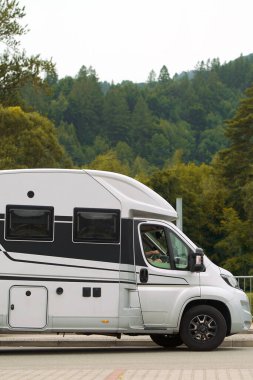 Ağaçlarla çevrili kırsal bir alanda park edilmiş bir karavan.