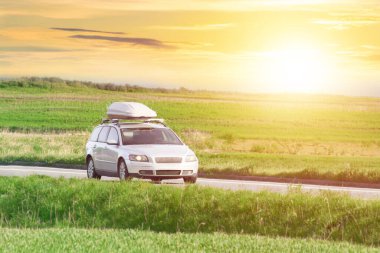 Vehicle with roofbox on country road clipart