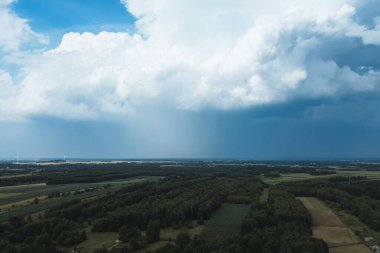 Fırtınalı bulutların altında uzanan yeşil alanlar