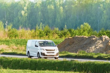 Beyaz kargo kamyonu kırsal yolda ilerliyor.