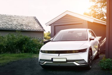 Banliyö bölgesinde park etmiş parlak beyaz elektrikli cip manzarası.