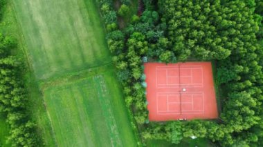 Kırmızı tenis kortu olan yeşil parkın havadan görünüşü