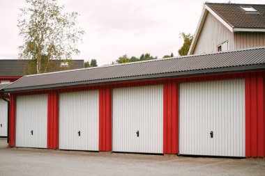 Banliyö bölgesinde beyaz kapıları olan kırmızı garaj birimleri.