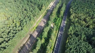 Ormanda paralel giden demiryolu ve yol, yukarıdan görüldü.