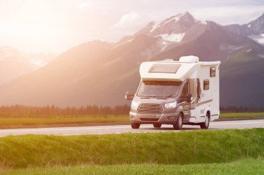 Motorlu ev, dağ zeminli çarpıcı bir gölün yanından geçiyor.