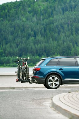 Kırsal yolda bisiklet taşıyan mavi bir araba.