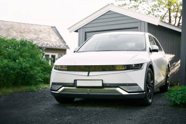 Banliyö evinin önüne park edilmiş elektrikli beyaz SUV.