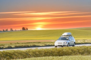 Road trip with roofbox through green hills clipart