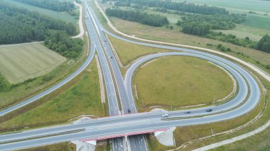 Arabalar ve yeşil manzaralı kırsal otoyol kavşağının yüksek görüntüsü