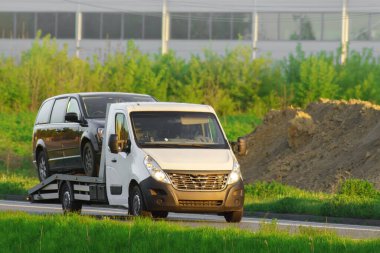 Gün batımında kırsal yolda SUV taşıyan bir çekici.