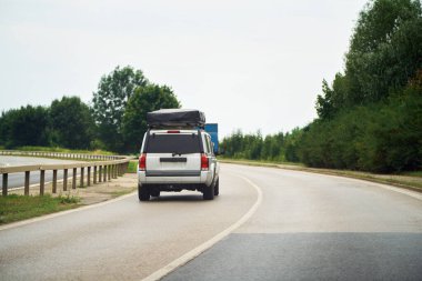 Çatısı kargo kutusu ve yolda uyku çadırı olan bir araba.