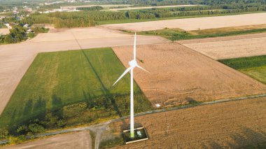 Gün batımında tarlaların arasında rüzgar türbini
