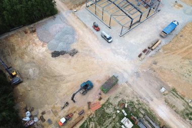 Kazı makinesi ve malzemelerle kırsal inşaat alanının hava görüntüsü.