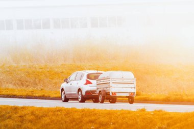 Arabası ve karavanı olan güneşli kır yolu.