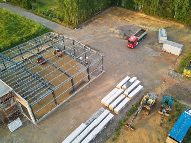 İnşaat alanı hava görüntüsü, kamyonlar ve çelik yapı.