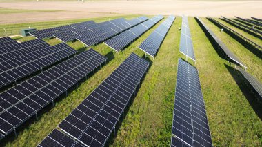 Güneş panelleri günbatımında sürdürülebilir enerji topluyor. Geniş bir güneş enerjisi santralinde temiz ve yenilenebilir enerji üretiyor.