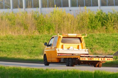 Kırsal kesimde gün batımı otoyolunda giden turuncu çekici.