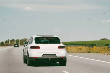 Beyaz araba açık bir yolda ilerliyor..