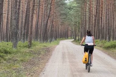 Bisikletli bir kadın kırsal alanda geziyor.